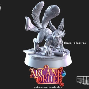 Può includere: Una statuetta in miniatura di volpe a tre code grigia con un'espressione ringhiante. La statuetta è in piedi su una base circolare con il testo "Arcane Order" e "patreon.com/castnplay".