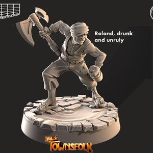 Peut inclure: Miniature imprimée en 3D d'un personnage nommé Roland, tenant une hache et une gourde. La figurine est sur une base pavée avec le texte "Roland, drunk and unruly". La base porte également le texte "Vol. 2 Townsfok".