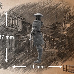 Puede incluir: Una figura en miniatura de pl&aacute;stico gris de un guerrero samur&aacute;i que lleva un sombrero c&oacute;nico y armadura. La figura mide 37 mm de alto y 11 mm de ancho. La figura est&aacute; de pie sobre un fondo gris con un dibujo de una calle japonesa.