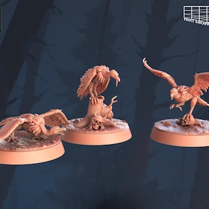 Puede incluir: Tres buitres en miniatura impresos en 3D, cada uno posado sobre una base. Los buitres están en varias poses, uno de pie sobre un tocón de árbol y otro posado sobre una calavera. Las miniaturas están pintadas en un color marrón claro.