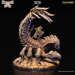 Könnte beinhalten: Eine bemalte Miniaturfigur von Seth, dem ägyptischen Gott des Chaos, der auf einem Skorpion reitet. Der Skorpion ist dunkelbraun mit goldenen Akzenten. Seth ist dunkelgrau mit goldenen Akzenten und hält einen Stab. Die Miniatur steht auf einem braunen Sockel.