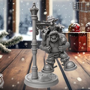 Puede incluir: Una miniatura gris impresa en 3D de una figura grande y musculosa que lleva una figura más pequeña sobre su espalda, junto a una farola. Las figuras visten ropa de invierno. La base de la farola tiene las palabras "Cast n Play".