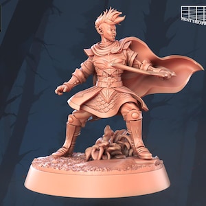 May include: A 3D printed miniature of a fantasy character, a warrior with pointed ears, wearing armour and a cape, holding a sword. The miniature is standing on a base with a textured surface.