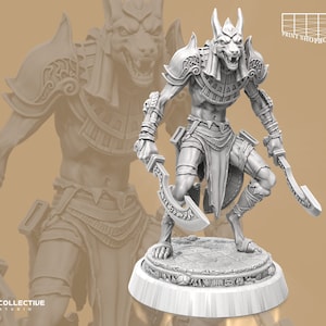Può includere: Una statuetta in miniatura grigia e dettagliata di una figura umanoide con testa di sciacallo con un'espressione feroce. La figura tiene due spade curve e indossa un costume dettagliato e stratificato con un colletto e una gonna. La figura è in piedi su una base circolare.
