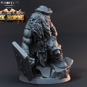 Op de afbeelding: Een grijs plastic miniatuurfiguur van een Orc-krijger met een schild en een baard. Het figuur staat op een rotsachtige basis. De tekst "The Ork Horde" is zichtbaar op de achtergrond.