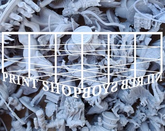 Op de afbeelding: Een verzameling grijze miniatuurbeeldjes, waaronder fantasiekarakters en -wezens. De tekst "PRINT SHOPBOY" is in een wit raster over de afbeelding geplaatst. De beeldjes lijken 3D-geprint te zijn.