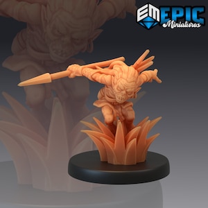 May include: A miniature goblin figurine holding a spear, standing on a grassy base. The goblin is painted in a light brown colour and has a fierce expression on its face. The base is also painted in a light brown colour and has a textured surface.