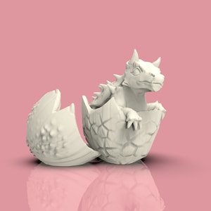 Könnte beinhalten: Eine weiße Keramik-Drachenfigur, die aus einem rissigen Ei schlüpft. Der Drache hat einen stacheligen Rücken und einen grimmigen Ausdruck.