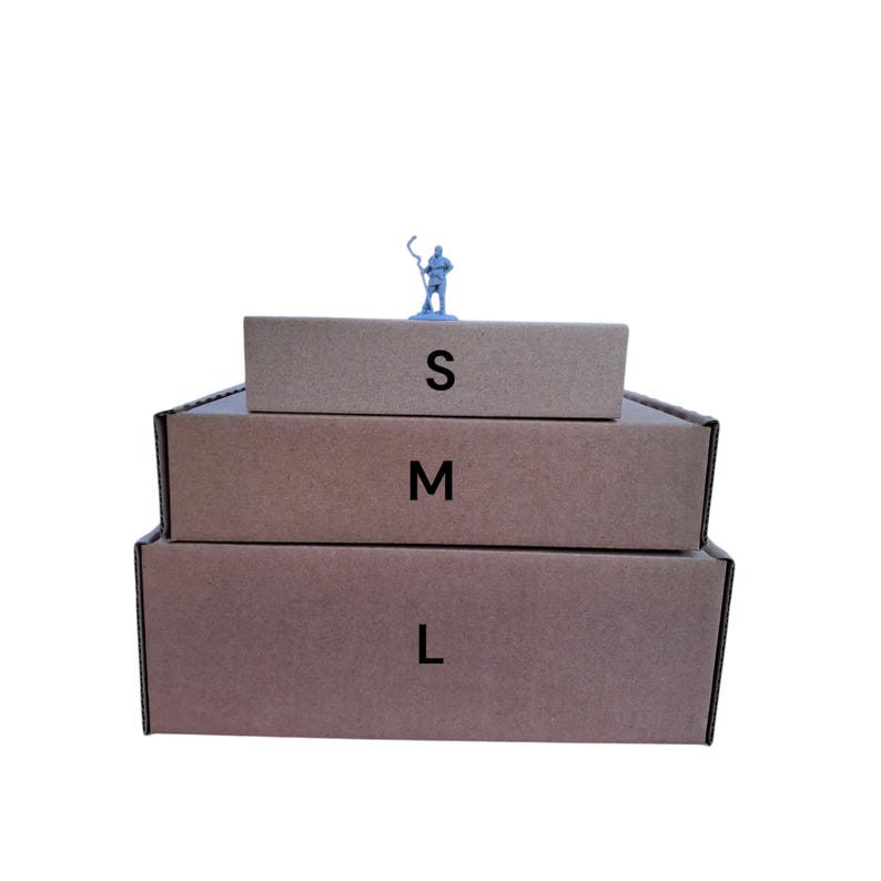 May include: Three stacked brown cardboard boxes labeled S, M, and L. A small blue figurine stands on the top box. The boxes are arranged in a stepped configuration, with the smallest box on top.