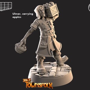 May include: A miniature figurine of a person carrying a basket and a crate of apples. The figurine is wearing a hooded cloak and is standing on a stone base. The text "Ulmar, carrying apples" is printed below the figurine.
