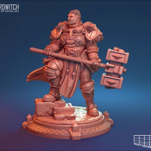 Könnte beinhalten: Eine detaillierte Miniaturfigur eines Kriegers in voller Rüstung, der einen großen Hammer hält. Die Figur ist in hellbrauner Farbe bemalt und steht auf einem Steinsockel.