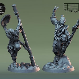 May include: Two grey painted miniature figurines of people in traditional Asian clothing. One figure holds a staff and the other holds a fan. Both figures are standing on a grey base.