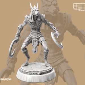 Könnte beinhalten: Eine weiße, detaillierte Miniaturfigur eines ägyptischen Gottes mit einem Schakal-Kopf, der zwei sichelförmige Waffen hält. Die Figur steht auf einem runden Sockel mit aufwendigen Designs.