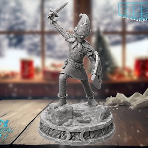 Può includere: Una statuetta grigia di un personaggio fantasy, che tiene una spada in alto e uno scudo. La figura è in piedi su una base dettagliata e strutturata. La statuetta è ambientata su uno sfondo sfocato di una finestra e una superficie di legno.
