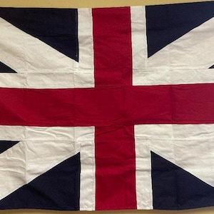 May include: A Union Jack flag, a British flag, with a red cross on a white background, and a blue background with white diagonal lines.