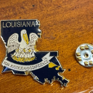 May include: A gold-colored Louisiana state outline pin with a white pelican and the state motto "Union Justice and Confidence".