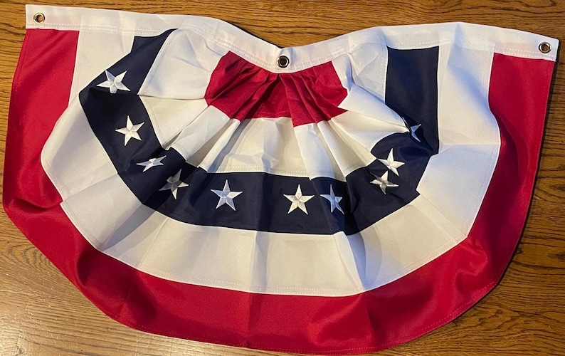 Puede incluir: Una guirnalda de banderines patri&oacute;tica roja, blanca y azul con un dise&ntilde;o plisado. La bandera presenta un borde rojo, un centro blanco y rayas azul marino con estrellas blancas. Tiene ojales para colgar.