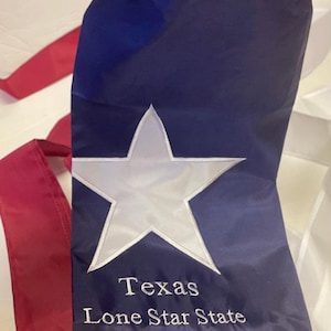 May include: A blue fabric windsock with a white star and the text "Texas Lone Star State" embroidered on it.