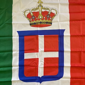 Puede incluir: Bandera italiana con franjas verticales verdes, blancas y rojas. El centro presenta un campo blanco con una corona roja y dorada sobre un emblema con borde azul con una cruz roja sobre fondo blanco.