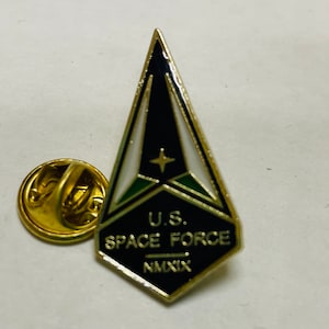 May include: A gold-colored pin with a black, white, and green delta-shaped design. The pin features the text "U.S. SPACE FORCE" and "MMXIX".