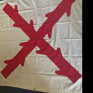 May include: A white flag with a large red cross, featuring stylized hand-like shapes at the ends of each arm. The flag is made of fabric and has grommets along the bottom edge.