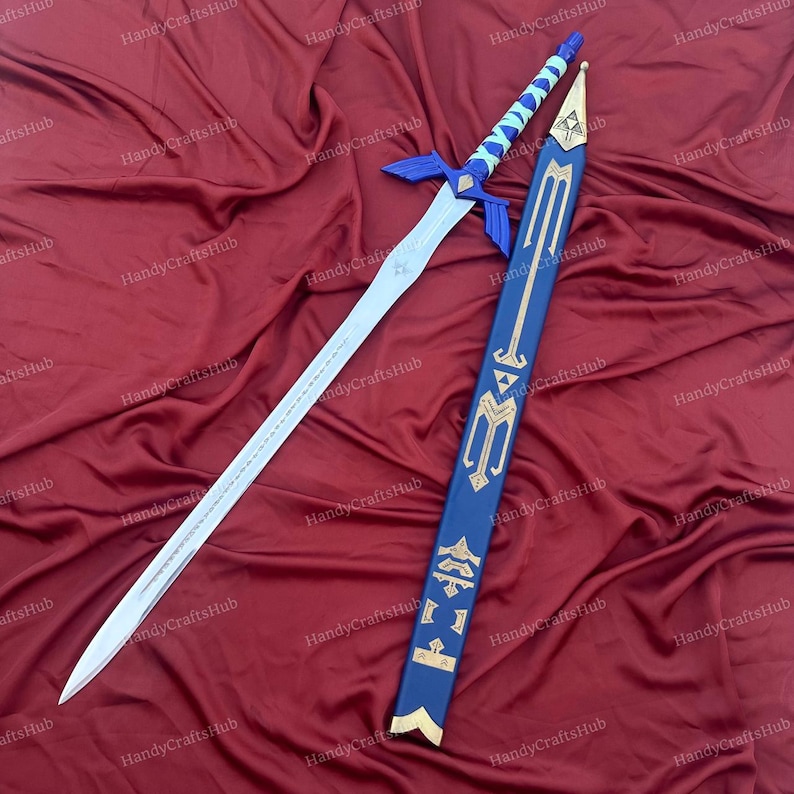 Puede incluir: Espada de fantas&iacute;a con dise&ntilde;o azul y plateado, con una vaina a juego. La espada presenta una hoja plateada, una guarda azul y un mango azul y blanco. La vaina es azul con detalles dorados.
