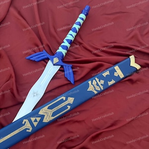 Puede incluir: Una espada de fantas&iacute;a azul y plateada con una hoja blanca y una vaina azul a juego. La espada presenta una empu&ntilde;adura azul con un agarre envuelto en verde claro. La vaina es azul con elementos decorativos dorados.