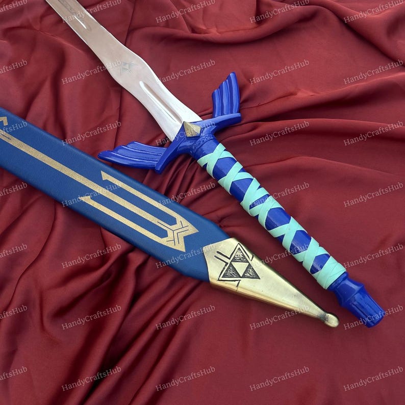 Puede incluir: Espada de fantas&iacute;a azul y plateada con vaina a juego. La espada presenta una hoja plateada, una empu&ntilde;adura azul con un acento en forma de diamante y un mango envuelto en azul y azul claro. La vaina es azul con detalles dorados.