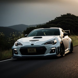 May include: A white Subaru BRZ sports car with a black hood scoop and a black rear spoiler. The car is driving on a winding road with green trees and hills in the background. The car has a yellow license plate that reads "1031M".
