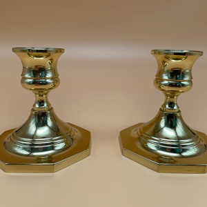 May include: A pair of gold-toned metal candle holders with octagonal bases and a simple, elegant design.