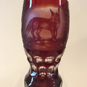 May include: A ruby red glass goblet with a cut crystal design. The goblet features an etched image of a fox in the center.