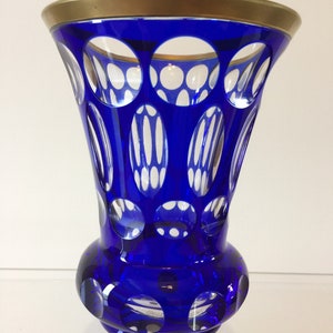 May include: A cobalt blue glass vase with a gold rim and a cut glass pattern. The vase has a round base and a flared top.