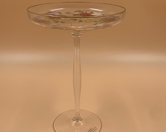 May include: A tall, clear glass pedestal bowl with a gold rim and floral design. The bowl has a delicate stem and a wide base.