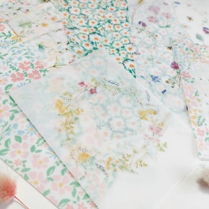 May include: Assortment of floral patterned papers with a calendar for April 2023. The papers are translucent and feature delicate floral designs in shades of pink, blue, and green.