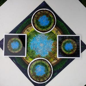 May include: Four round coasters with a blue and green concentric circle design. The coasters are arranged in a square pattern on a black background with white stars.