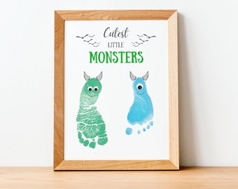 May include: A framed print featuring two monster footprints in green and blue. The green footprint has a smiling face, while the blue footprint has a single eye. The words "Cutest Little Monsters" are printed above the footprints in black and green.