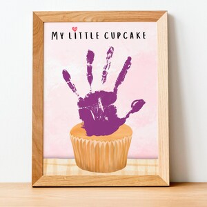 May include: A framed print with a purple handprint on a cupcake. The print says "My Little Cupcake".