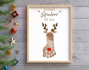 May include: A white framed printable with the text "Cutest Reindeer of All" and a brown reindeer footprint with a red nose and holly.