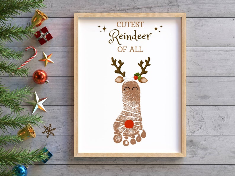 May include: A white framed printable with the text "Cutest Reindeer of All" and a brown reindeer footprint with a red nose and holly.