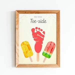 May include: Wooden framed print with the text "My little Toe-sicle". The artwork features a red footprint and three popsicle illustrations: lemon, a red popsicle, and watermelon. The background is a light yellow.