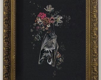 May include: A framed artwork featuring a silver bat hanging upside down, surrounded by colorful flowers against a black background. The frame is ornate with a gold finish, adding a vintage aesthetic.