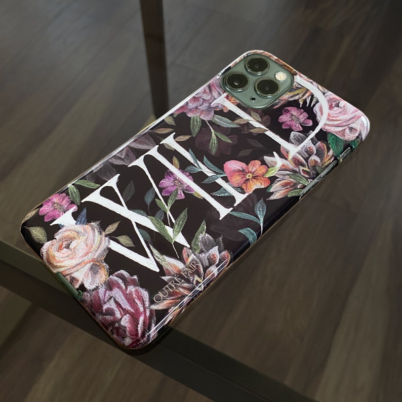 May include: A black phone case with a floral design and the word "WILD" in white lettering. The case is made by Outre Fair.