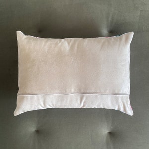May include: A plain, light gray throw pillow with a white zipper on the back.