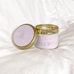 May include: A gold candle tin with a purple label that says "Tinderbellx Beauty Regime". The label features a cartoon illustration of a fairy.