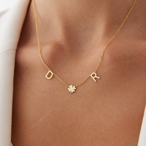 May include: Gold necklace with a four-leaf clover charm and initial letters D and R.