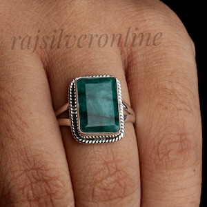 Może przedstawiać: Biały ceramiczny kubek z czarnym uchwytem i napisem "But First, Coffee" czarną, pogrubioną czcionką. Kubek stoi na drewnianej powierzchni. Kubek ma około 10 cm wysokości.