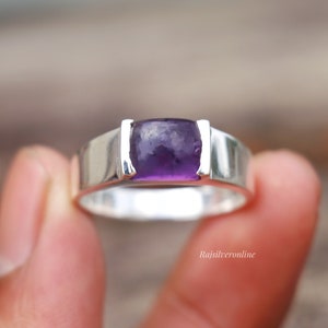 May include: A silver ring featuring a purple amethyst gemstone. The ring has a straightforward design with a rectangular setting for the stone.