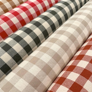 Può includere: Primo piano di diversi rotoli di tessuto con un classico motivo a quadretti. I rotoli di tessuto mostrano una varietà di colori, tra cui rosso, nero, beige e ruggine, tutti con quadrati bianchi. Il tessuto è adatto a vari progetti di cucito e decorazione.