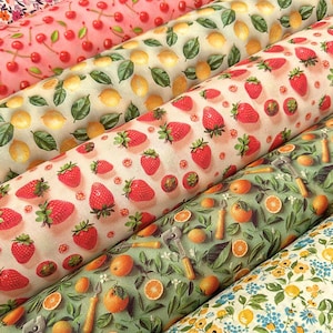 May include: A collection of rolled fabric bolts featuring various fruit and floral patterns. Designs include cherries, lemons, strawberries, oranges, and small blue flowers. The fabrics are in shades of pink, green, and yellow.