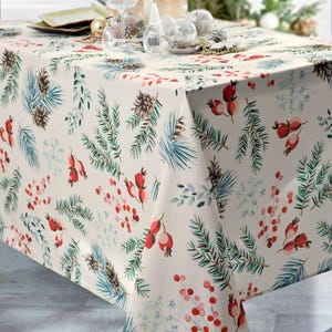 Peut inclure: Une nappe blanche avec un motif de Noël festif représentant des branches de pin, des pommes de pin et des baies rouges.